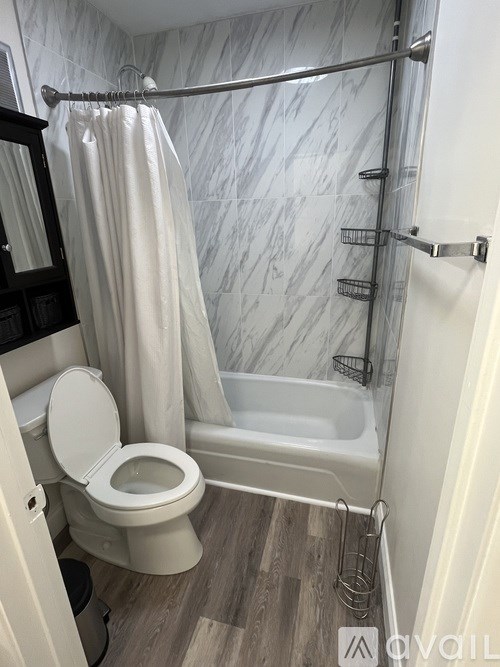 A white toilet in a bathroom with a marble wall.