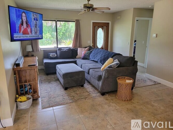 A living room with a grey couch and a flat screen TV mounted on the wall.