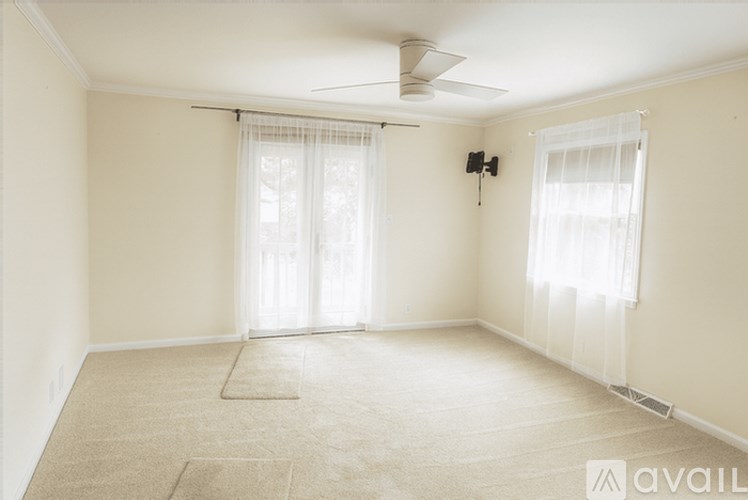 A spacious room with a fan and two windows.