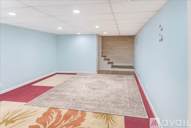 A room with a staircase in the background and a rug on the floor.