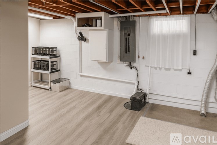 A room with wooden flooring and a white wall with a vent and a hose.