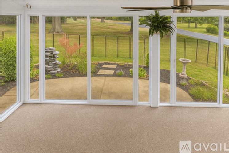 A patio with a fan and a view of a yard.