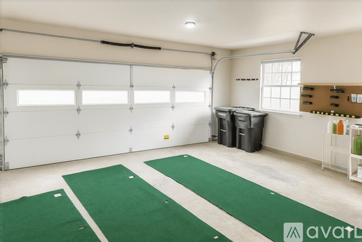 A garage with green mats on the floor and a white wall.