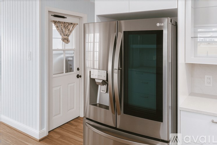 A modern kitchen with a stainless steel refrigerator and white cabinetry.