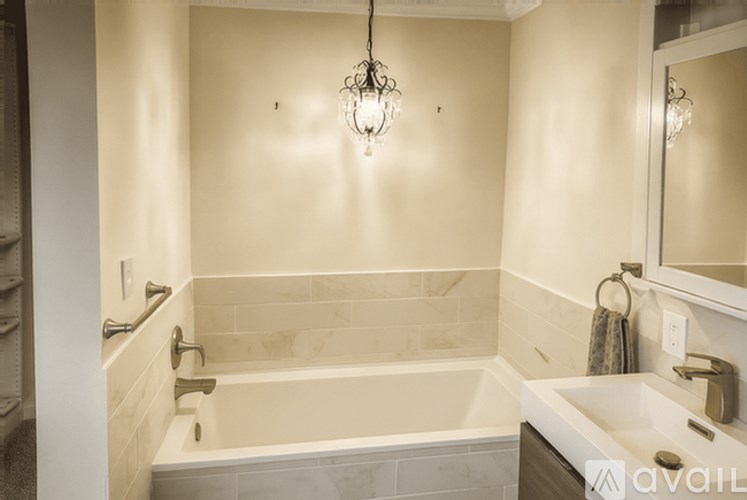 A bathroom with a tub, sink, and mirror.