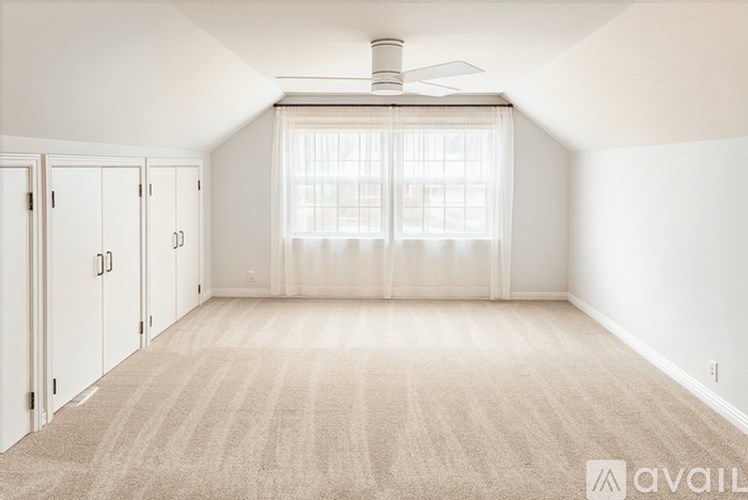 A room with a carpeted floor and a ceiling fan.