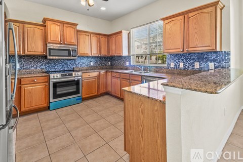 A kitchen with wooden cabinets and a blue backsplash.