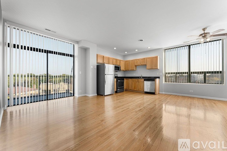 A spacious kitchen and living room with wooden floors and large windows.