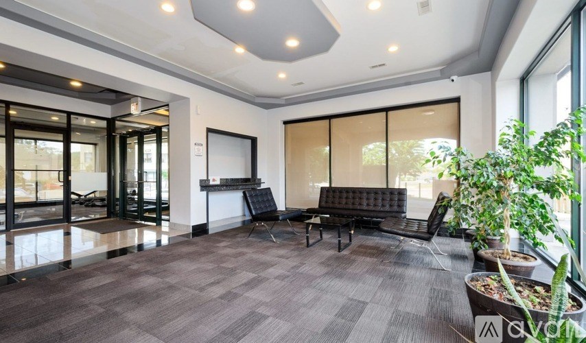 A spacious room with a grey carpet and a black sofa.