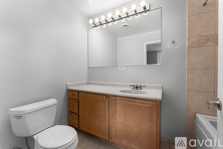 A bathroom with a white toilet, a wooden cabinet, and a sink with a mirror above it.
