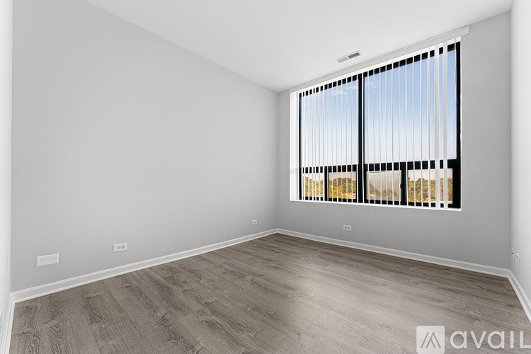 A room with wooden flooring and a window with blinds.