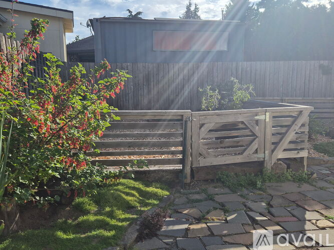 A wooden gate is in front of a fence and a house.