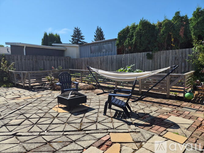 A backyard with a hammock, chairs, and a fire pit.