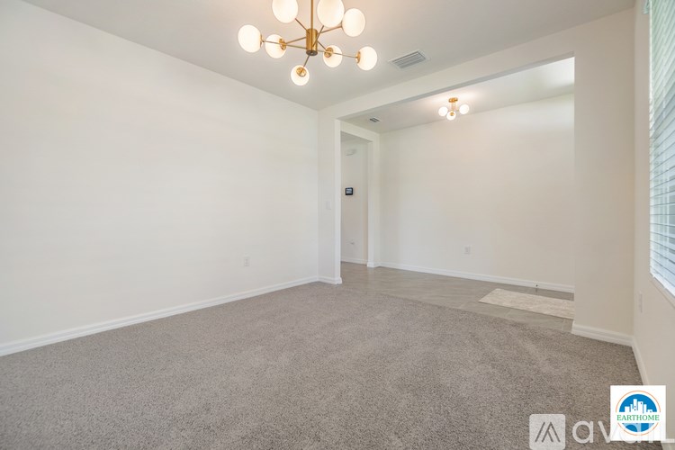 A spacious room with a carpeted floor and a chandelier.