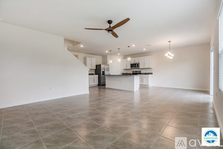 A spacious kitchen and living room with a fan and track lighting.