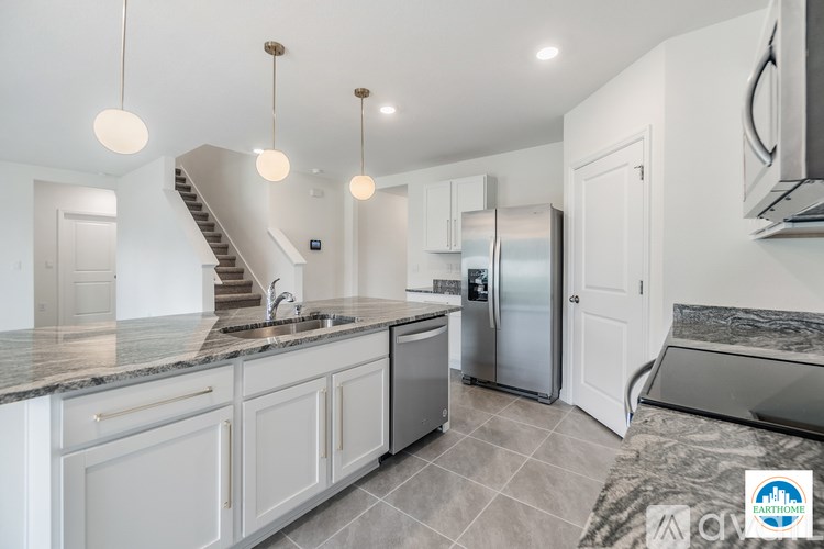 A modern kitchen with a marble countertop and stainless steel appliances.