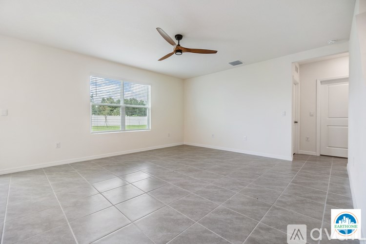 A spacious room with a ceiling fan and a large window.