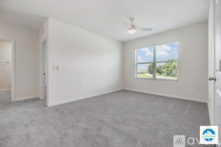 A spacious room with a carpeted floor and a ceiling fan.