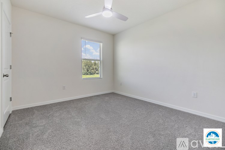 A room with a ceiling fan and a window with blinds.