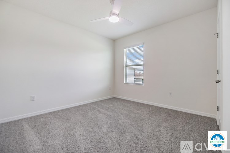 A room with a carpet floor and a ceiling fan.
