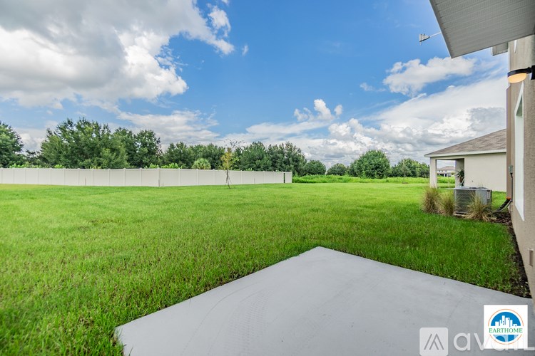 A large open field with a building and a driveway in the foreground.