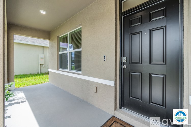 A black door is on the right side of a concrete wall.