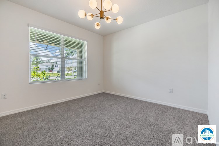 A well lit room with a carpeted floor and a window with blinds.