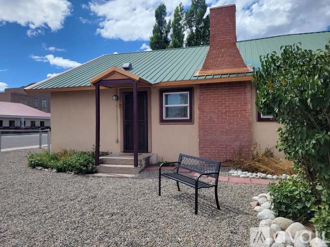 A small house with a green roof and a bench in front.