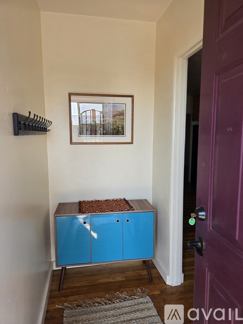 A room with a purple door and a blue cabinet.