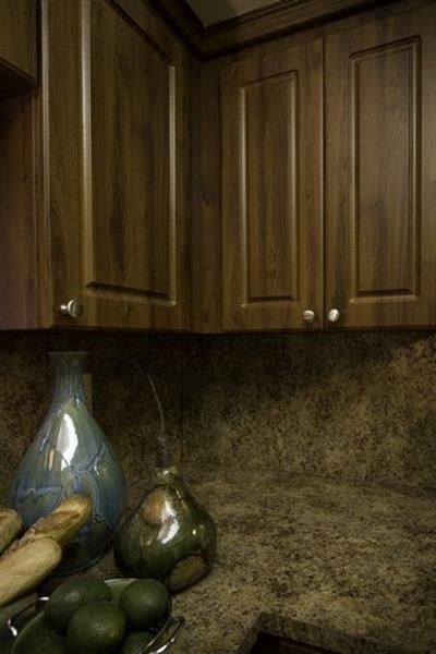 A kitchen with wooden cabinets and a bowl of green fruit.