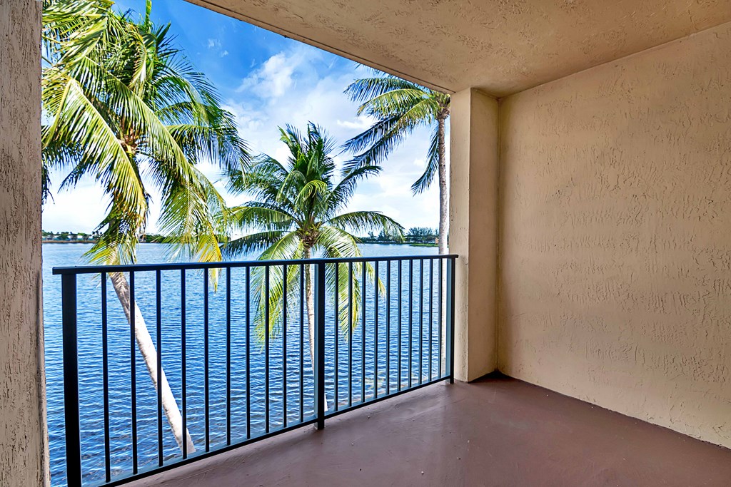 a balcony with a view of the water and palm trees
