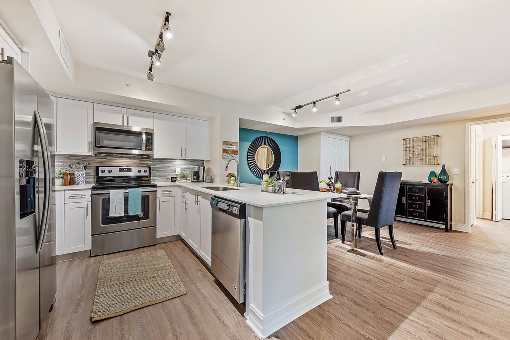 an open kitchen and dining room with stainless steel appliances and a white counter top