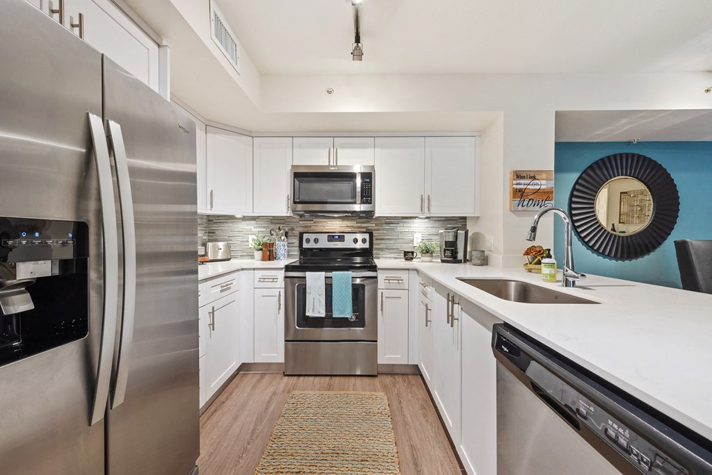 a modern kitchen with stainless steel appliances and white cabinets