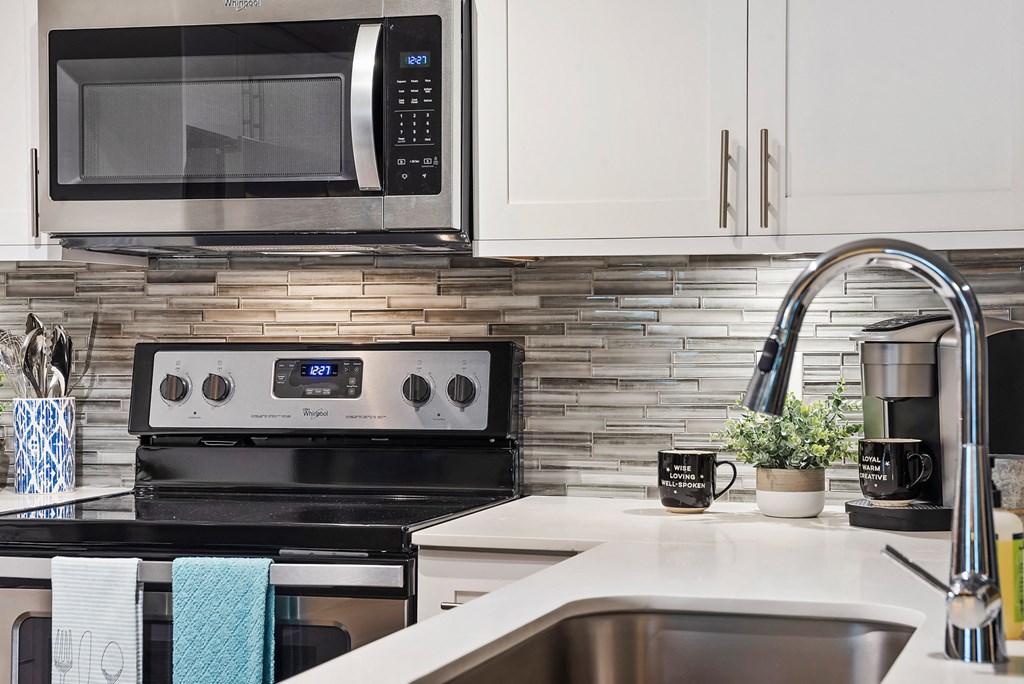 a kitchen with white cabinets and a black stove and a microwave
