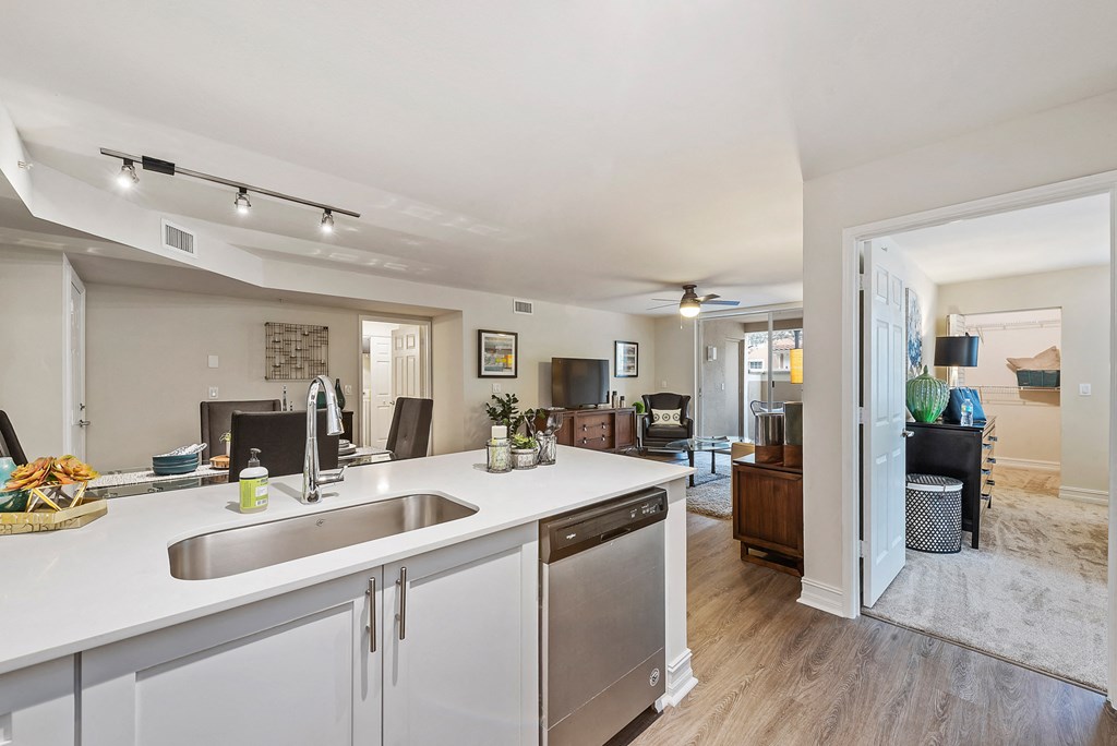 a kitchen with white counter tops and a sink and a living room