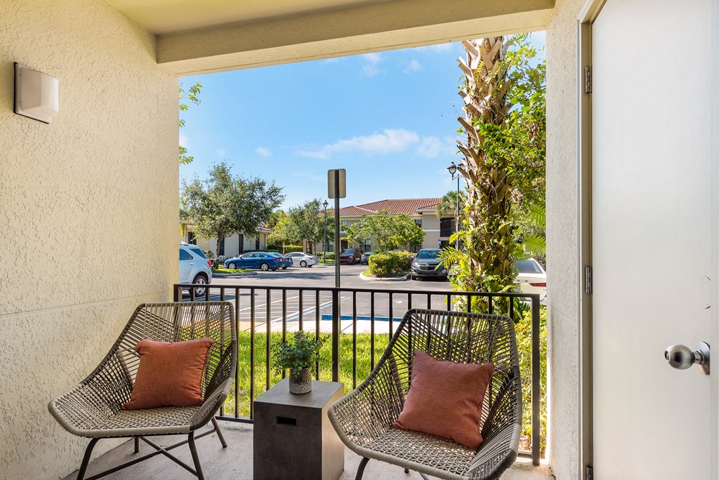 a balcony with two chairs and a view of a parking lot