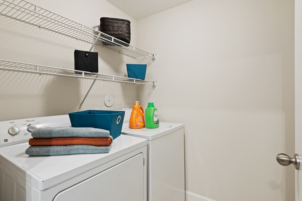 a laundry room with a washer and dryer and a rack on the wall