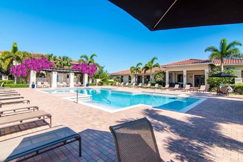 a swimming pool with lounge chairs and a building in the background