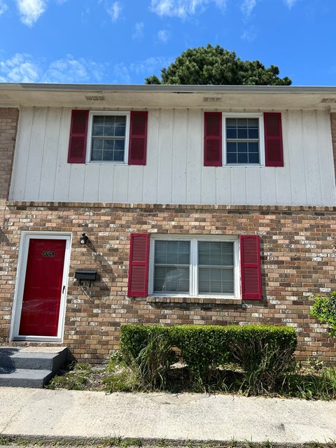 A red door and red shutters on a white house.