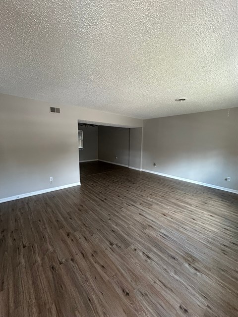 A room with wooden flooring and a doorway leading to another room.