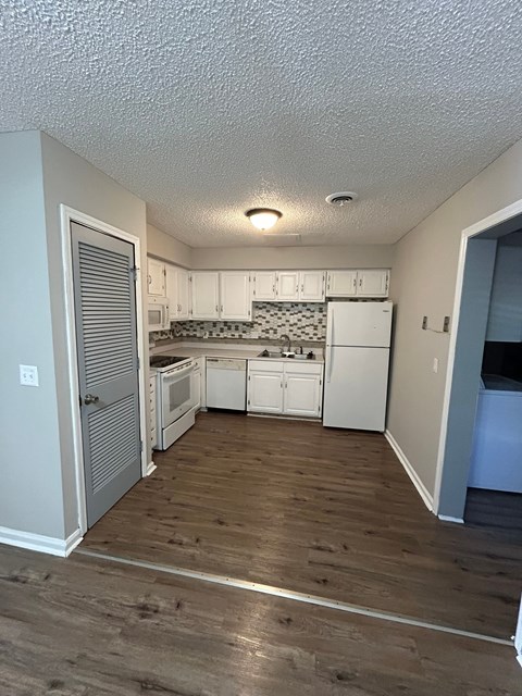 A kitchen with white cabinets and a wooden floor.