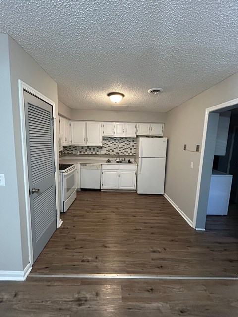 A kitchen with white cabinets and a black and white backsplash.