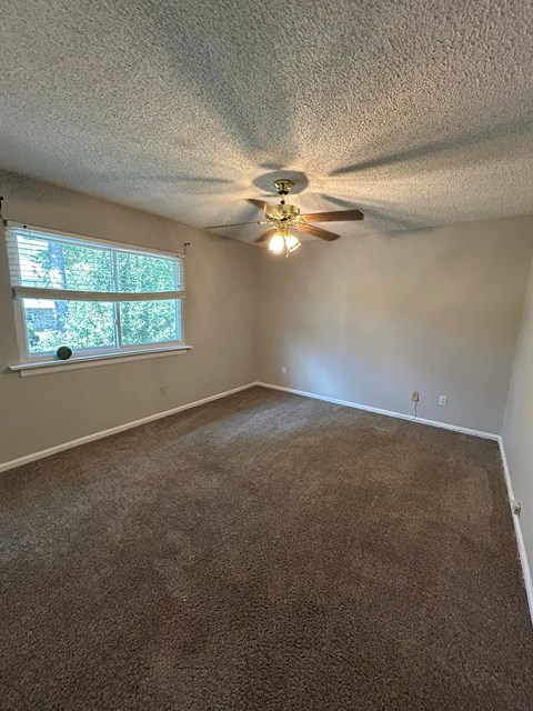 A room with a ceiling fan and carpeted floor.