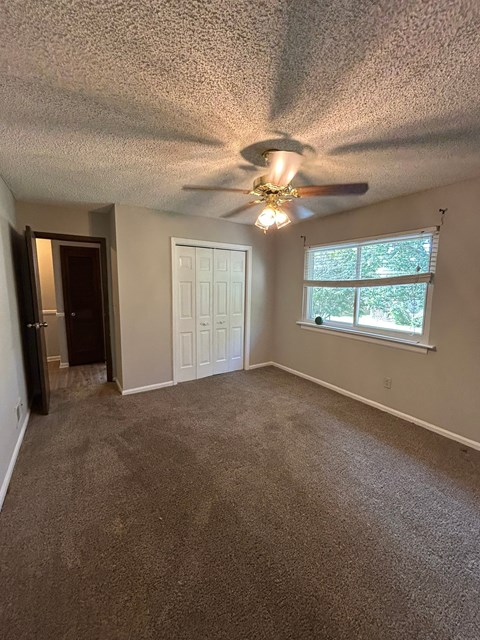 A room with a ceiling fan and carpeted floor.