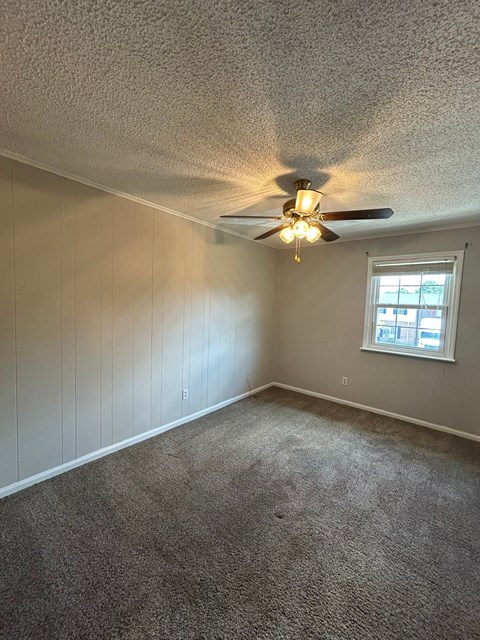 A room with a ceiling fan and a window.