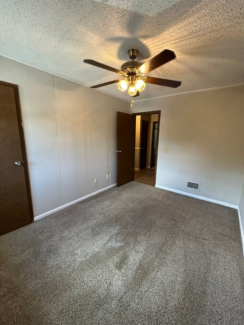 A room with a ceiling fan and carpeted floor.