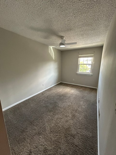 A room with a carpeted floor and a window.