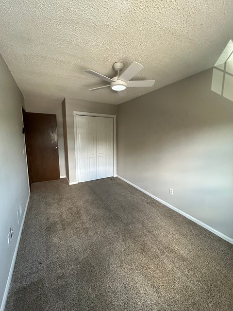 A room with a ceiling fan and carpeted floor.