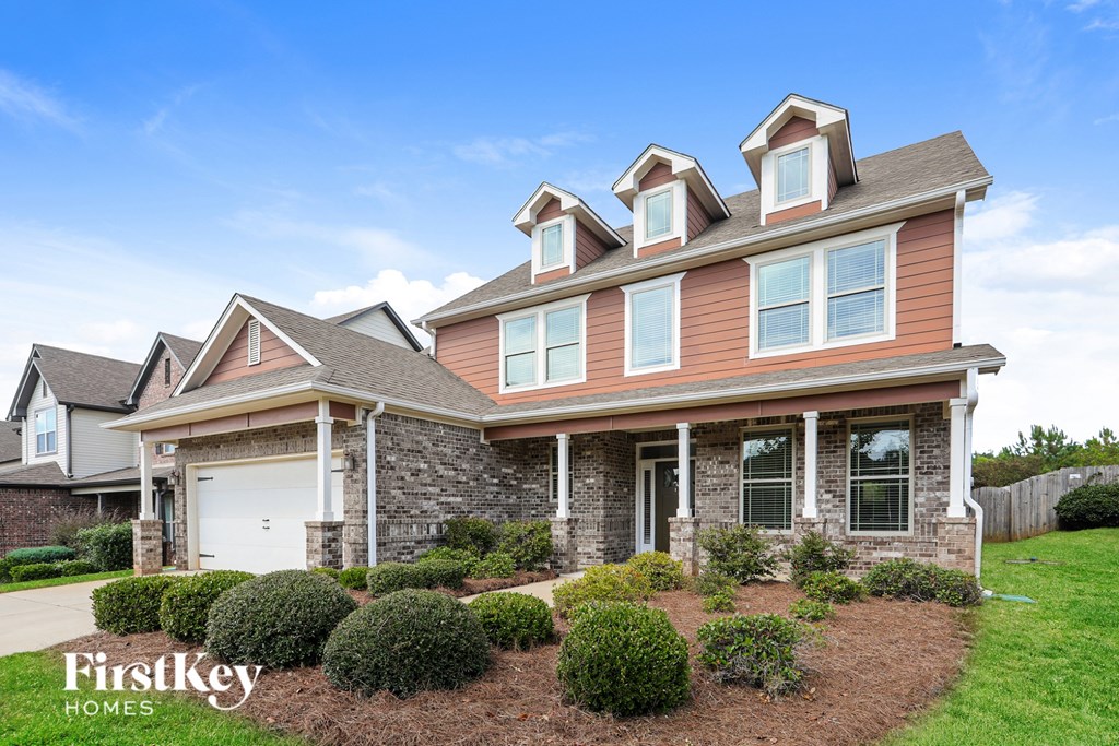 A house with a brown and beige exterior and a white garage door.