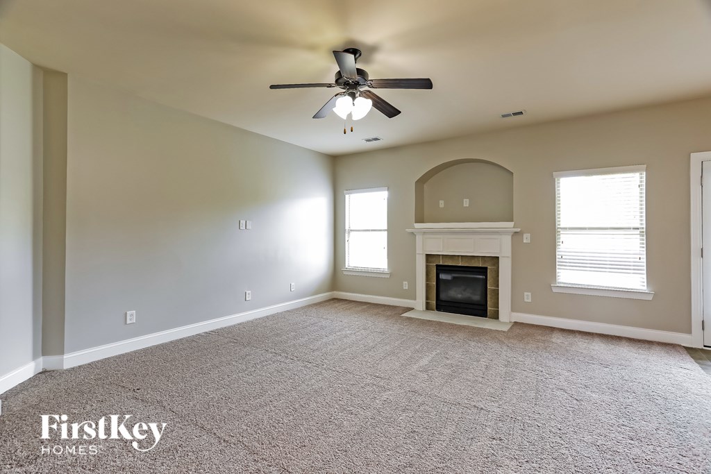 A spacious living room with a fireplace and a ceiling fan.
